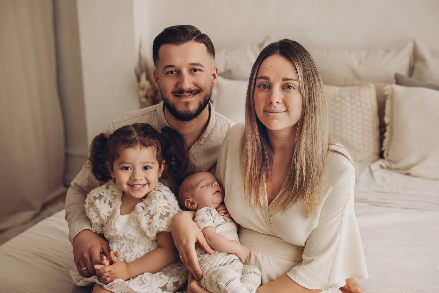 Familie mit Baby und Kleinkind sitzt zusammen für ein natürliches Familienfoto im Fotostudio