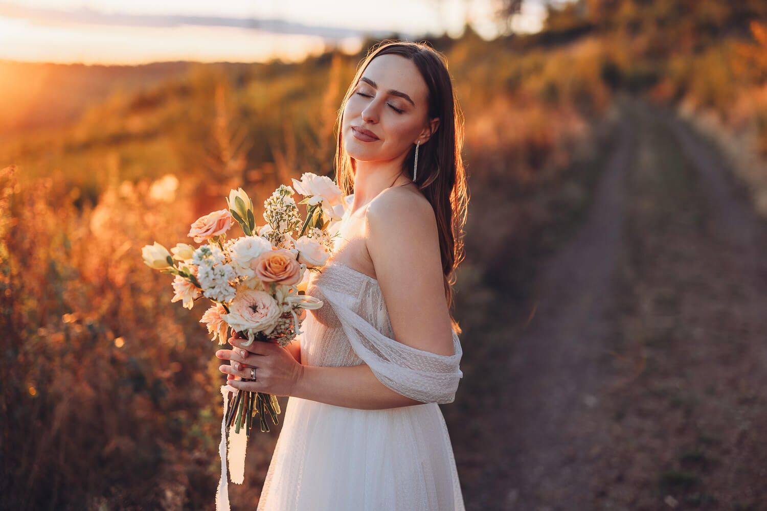Braut mit zartem Blumenstrauß genießt den Sonnenuntergang bei einem romantischen Hochzeitsshooting in Hameln und Hannover