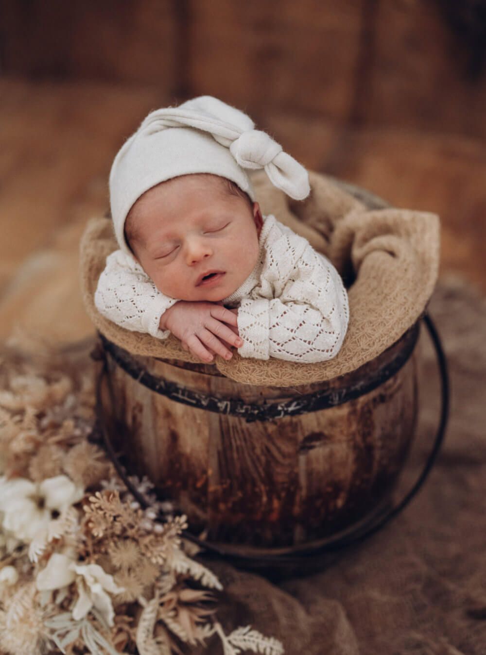 Liebevolles Newborn Shooting in Celle – schlafendes Baby in einem rustikalen Holzfass fotografiert