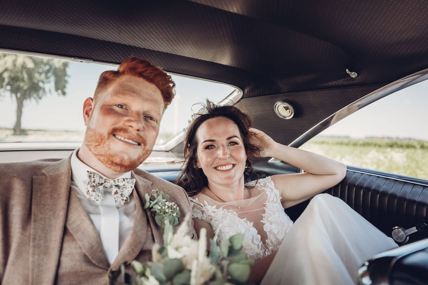 Frisch verheiratetes Brautpaar lächelt gemeinsam im Oldtimer während seiner Hochzeit in Pattensen - Hochzeitsfotograf aus Hannover