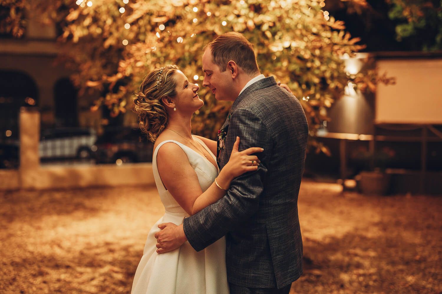 Brautpaar steht innig bei warmem Abendlicht unter Lichterketten, romantisch fotografiert von einem Hochzeitsfotografen aus Hannover