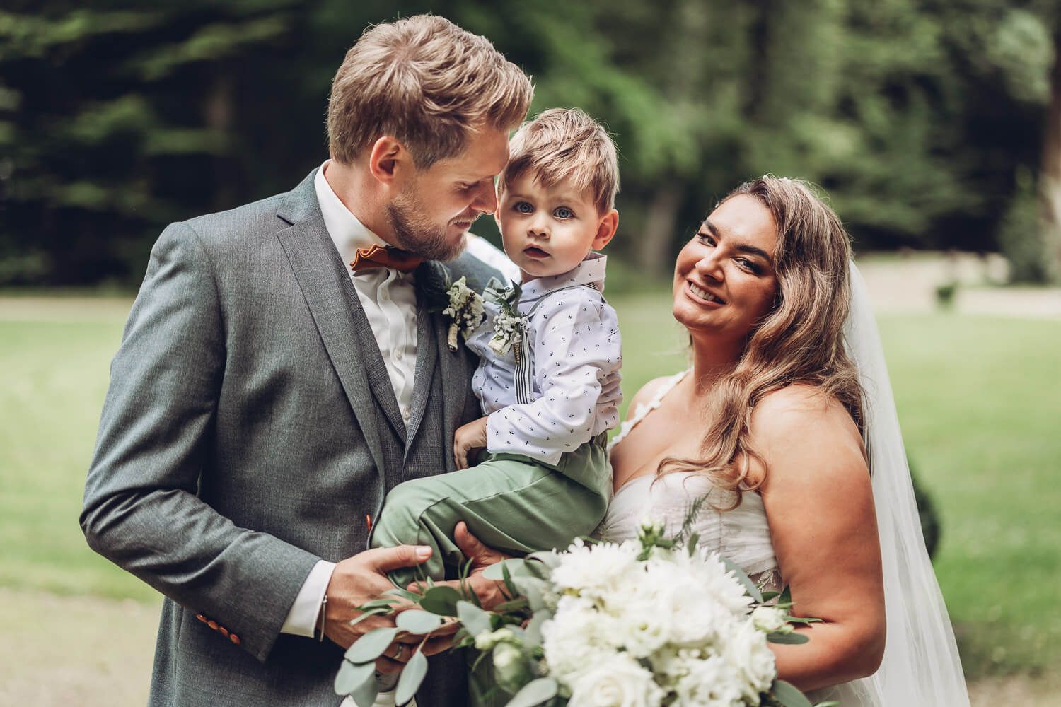 Brautpaar mit Kind bei einem entspannten Familienportrait während der Hochzeit - Hochzeitsfotograf Celle
