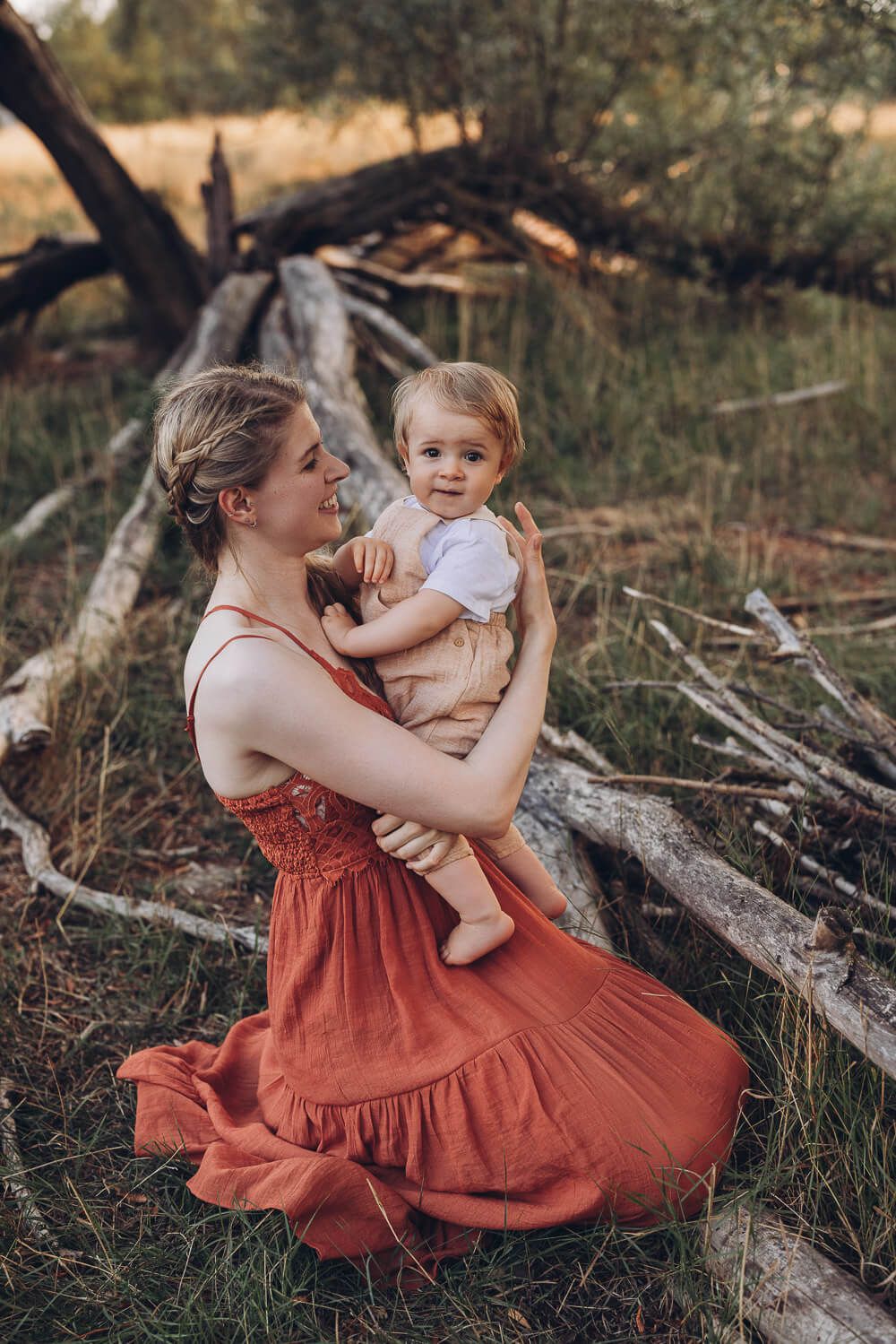 Liebevolles Portrait beim Outdoorfotoshooting Hannover, Mutter hält ihr Baby im Arm vor einer natürlichen Waldkulisse