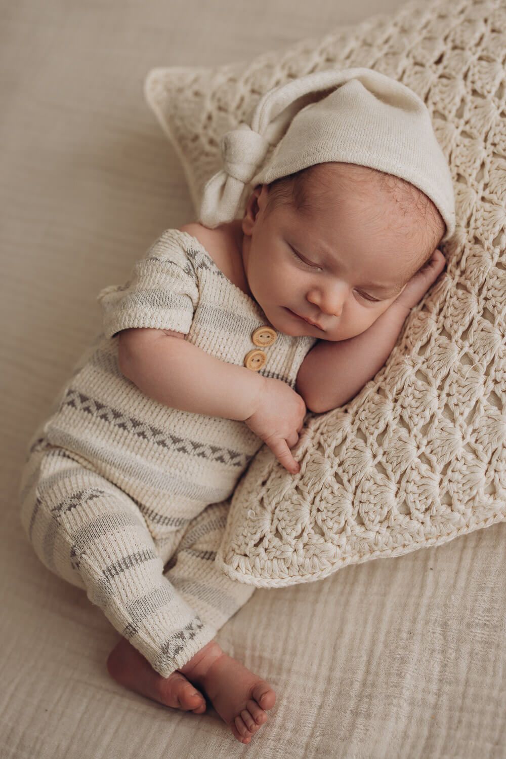 Schlafendes Baby liegt entspannt auf einem weichen Kissen beim Newborn Shooting