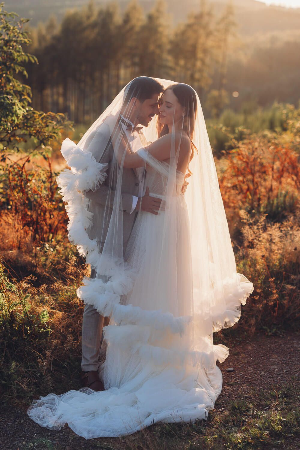 Braut und Bräutigam stehen eng umschlungen unter einem zarten Schleier im goldenen Abendlicht bei einem Hochzeitsshooting in Hannover