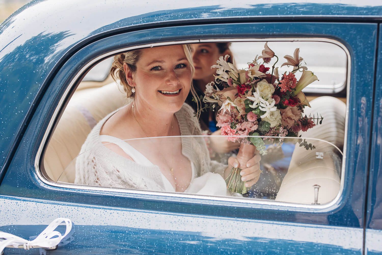 Braut sitzt mit Brautstrauß im Oldtimer nach der Hochzeit in Braunschweig
