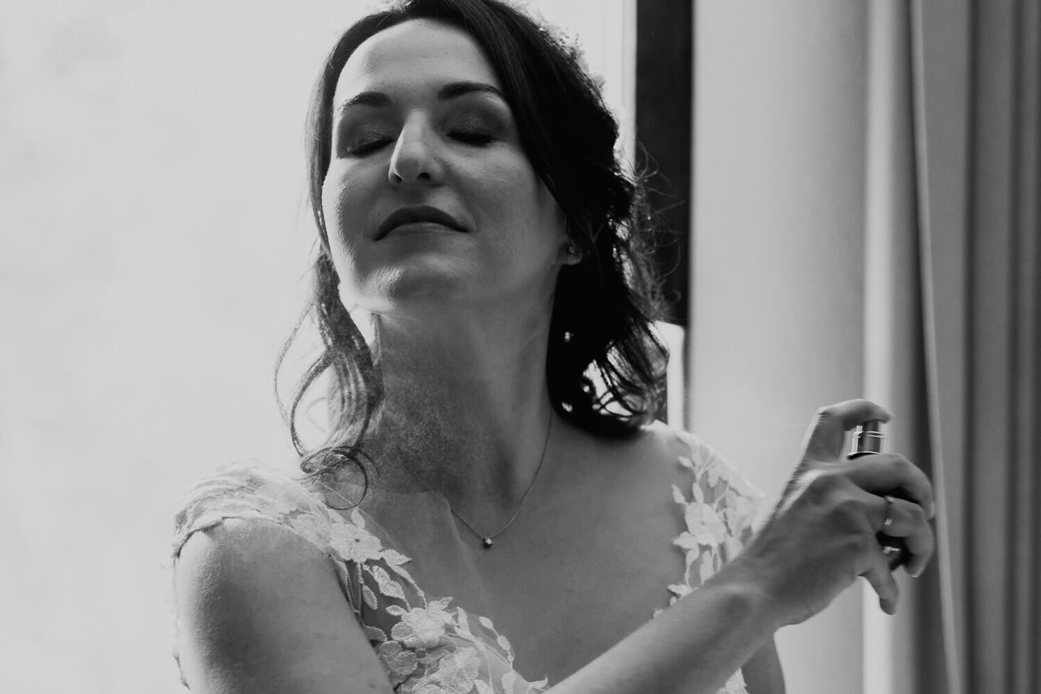 Schwarzweißaufnahme der Braut beim Auftragen von Parfum während des Getting Ready. Hochzeitstreportage Foto in Hannover