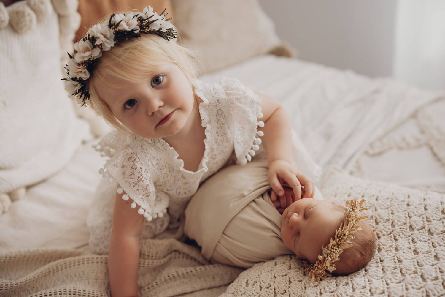 Liebevolles Geschwisterbild beim Newborn Shooting in der Wedemark – große Schwester liegt neben ihrer schlafenden Schwester im Boho Stil
