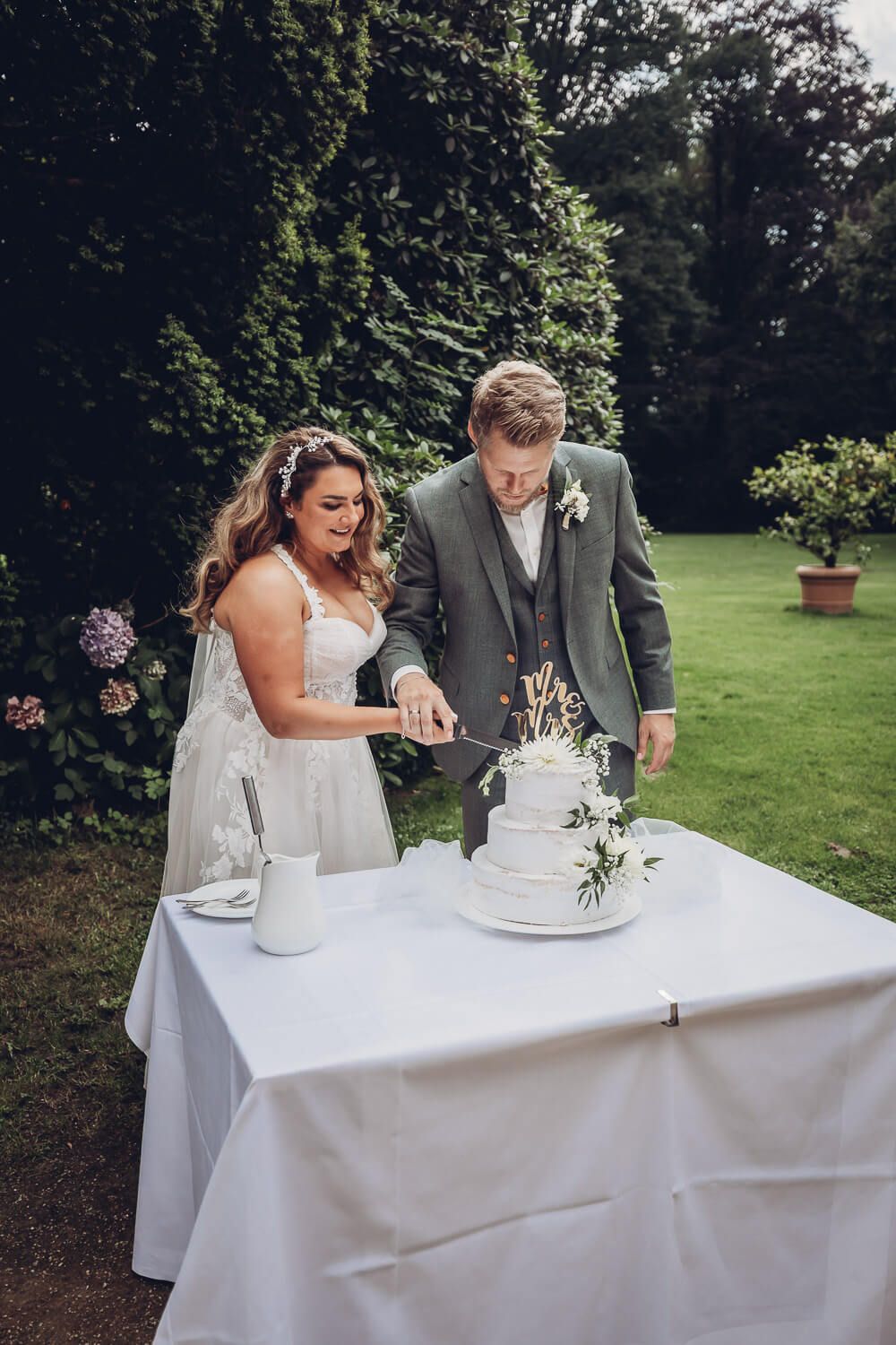Brautpaar beim feierlichen Anschnitt der Hochzeitstorte unter freiem Himmel, fotografiert von einem Fotografen in Hannover