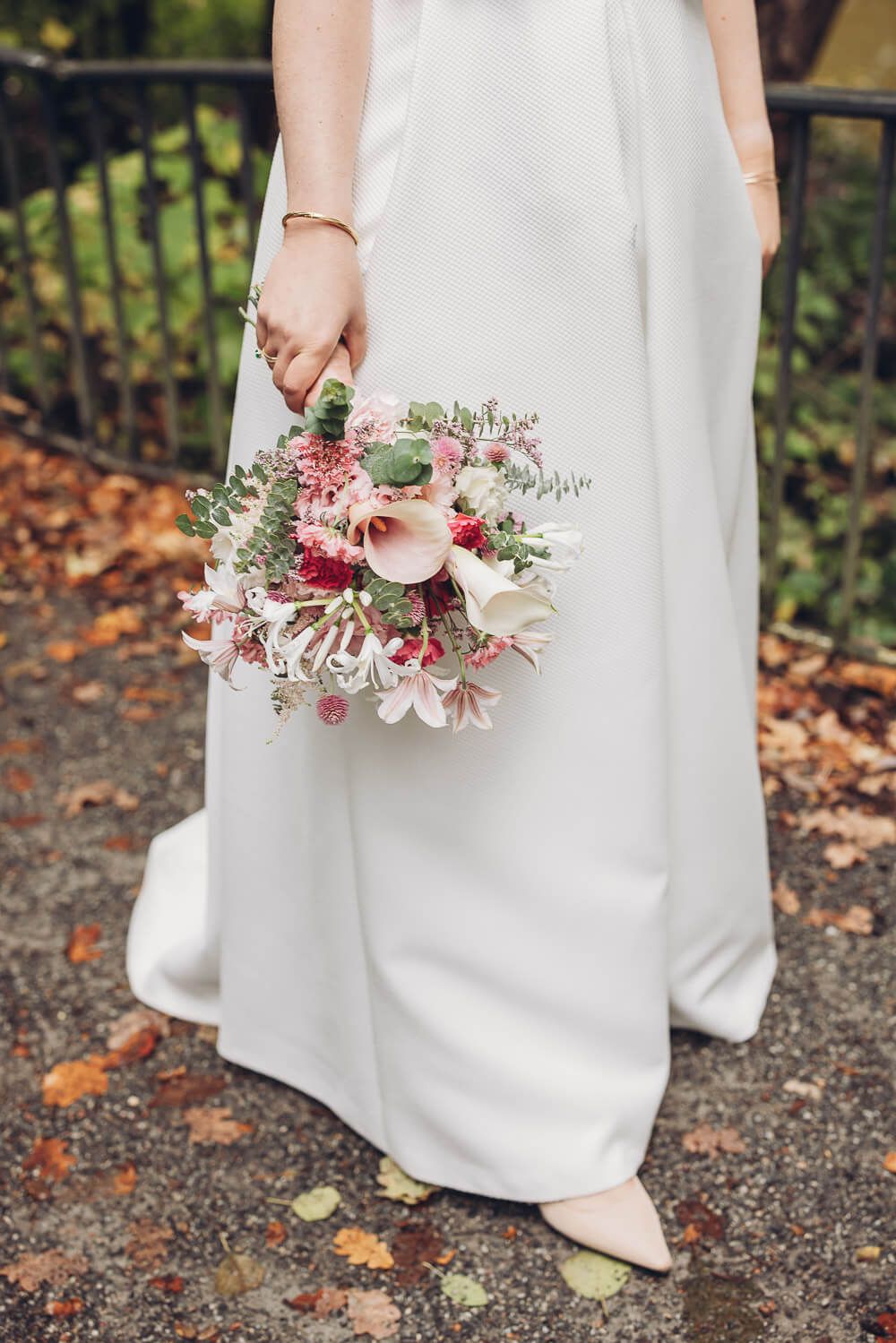 Braut hält einen farbenfrohen Brautstrauß vor ihrem weißen Hochzeitskleid bei einem Fotoshooting in Peine
