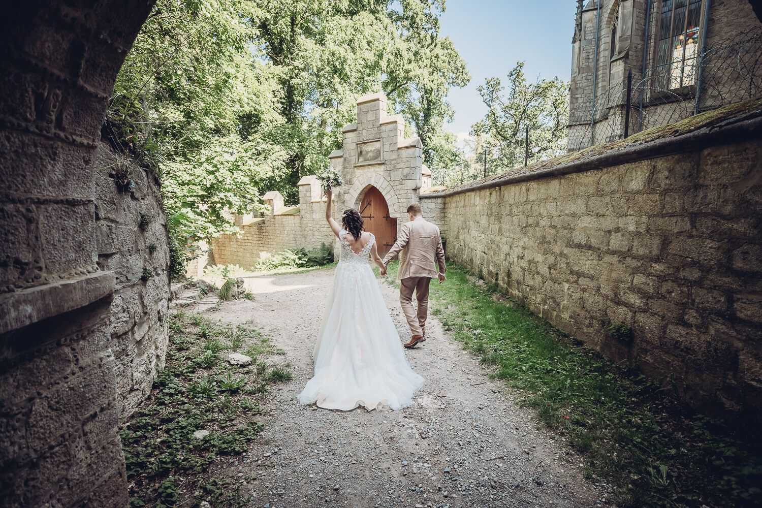Brautpaar geht Hand in Hand durch einen historischen Torweg an der Schloss Marienburg bei Pattensen - Hochzeitsfotograf aus Hannover