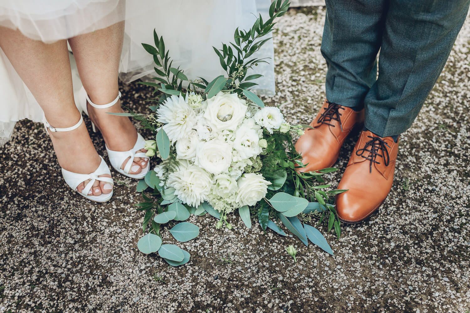 Brautstrauß zwischen Brautschuhen und Herrenschuhen als stilvolles Hochzeitsdetail, fotografiert von einem Hochzeitsfotografen in Hannover