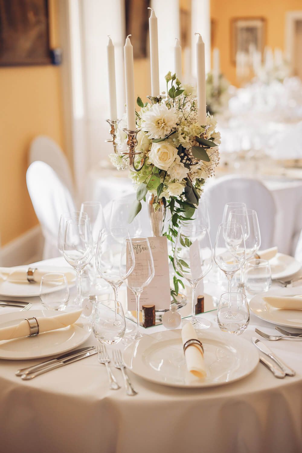 Elegante Hochzeitstischdekoration mit Kerzenleuchter, weißen Blumen und festlich gedecktem Tisch in Hannover - Hochzeitsfotograf Hameln