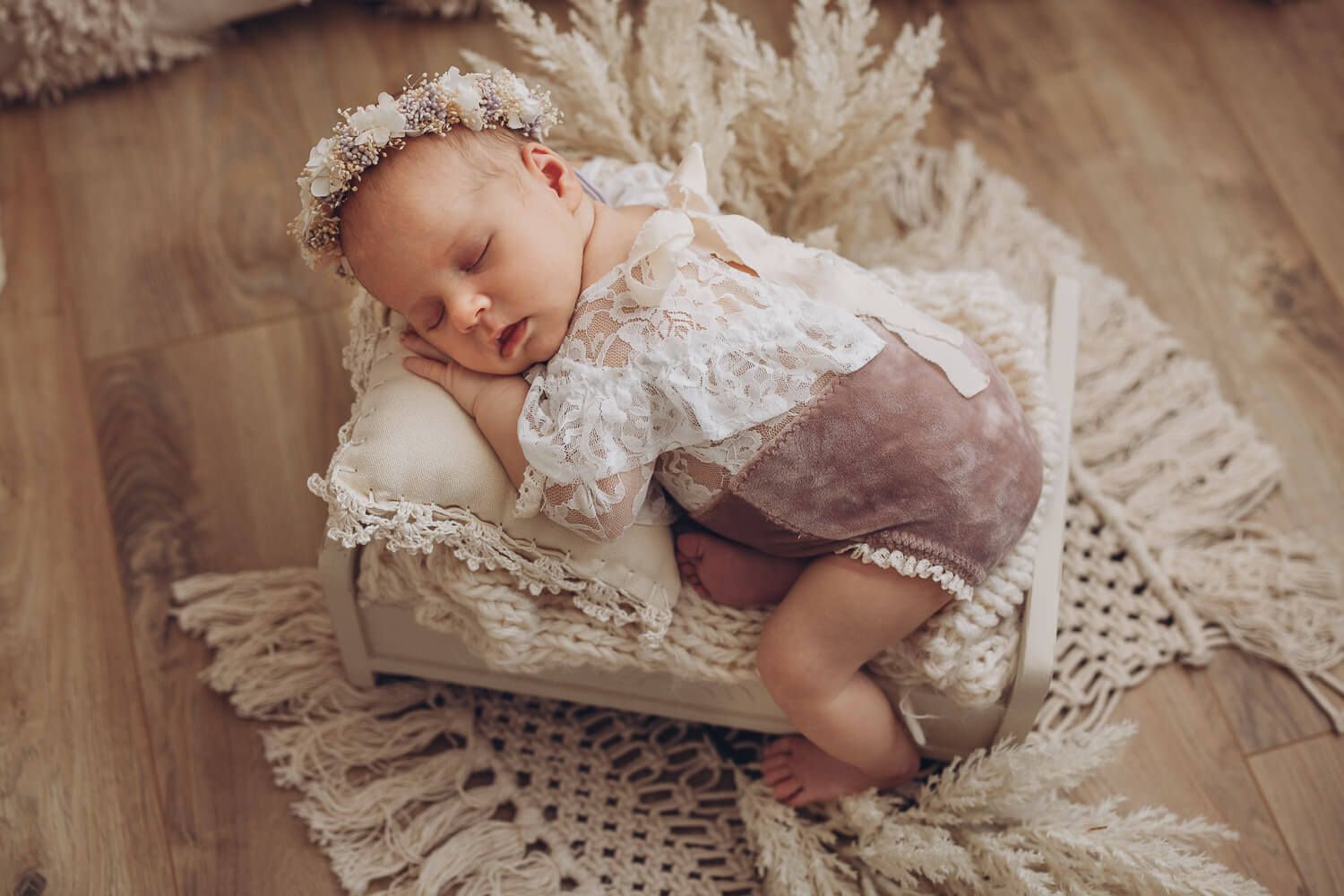 Babyfotografie in Langenhagen – Neugeborenes schläft entspannt auf einem kleinen Bett im Boho Stil