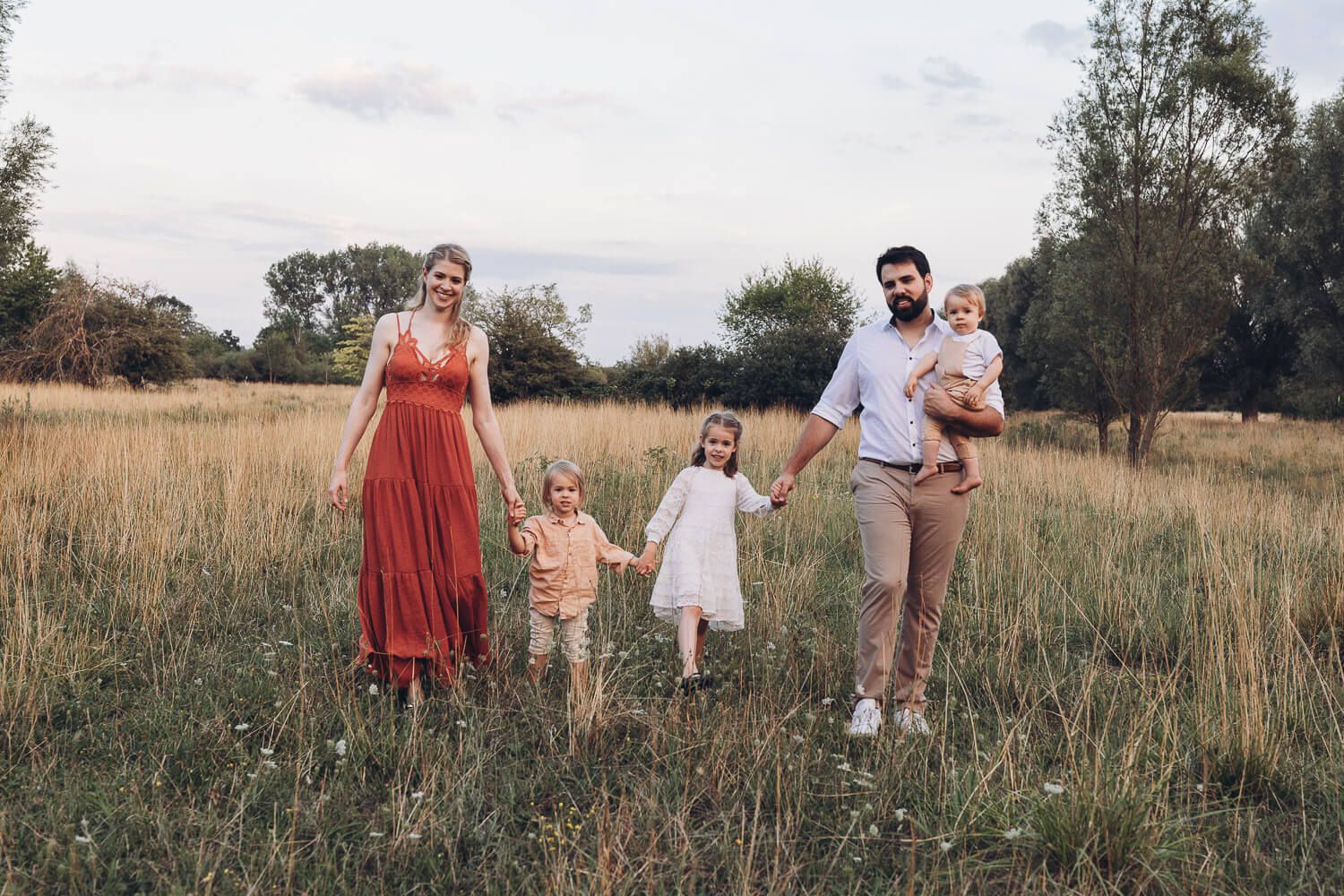 Familie läuft gemeinsam durch eine weite Wiese beim Outdoorfotoshooting Hildesheim in warmem Abendlicht