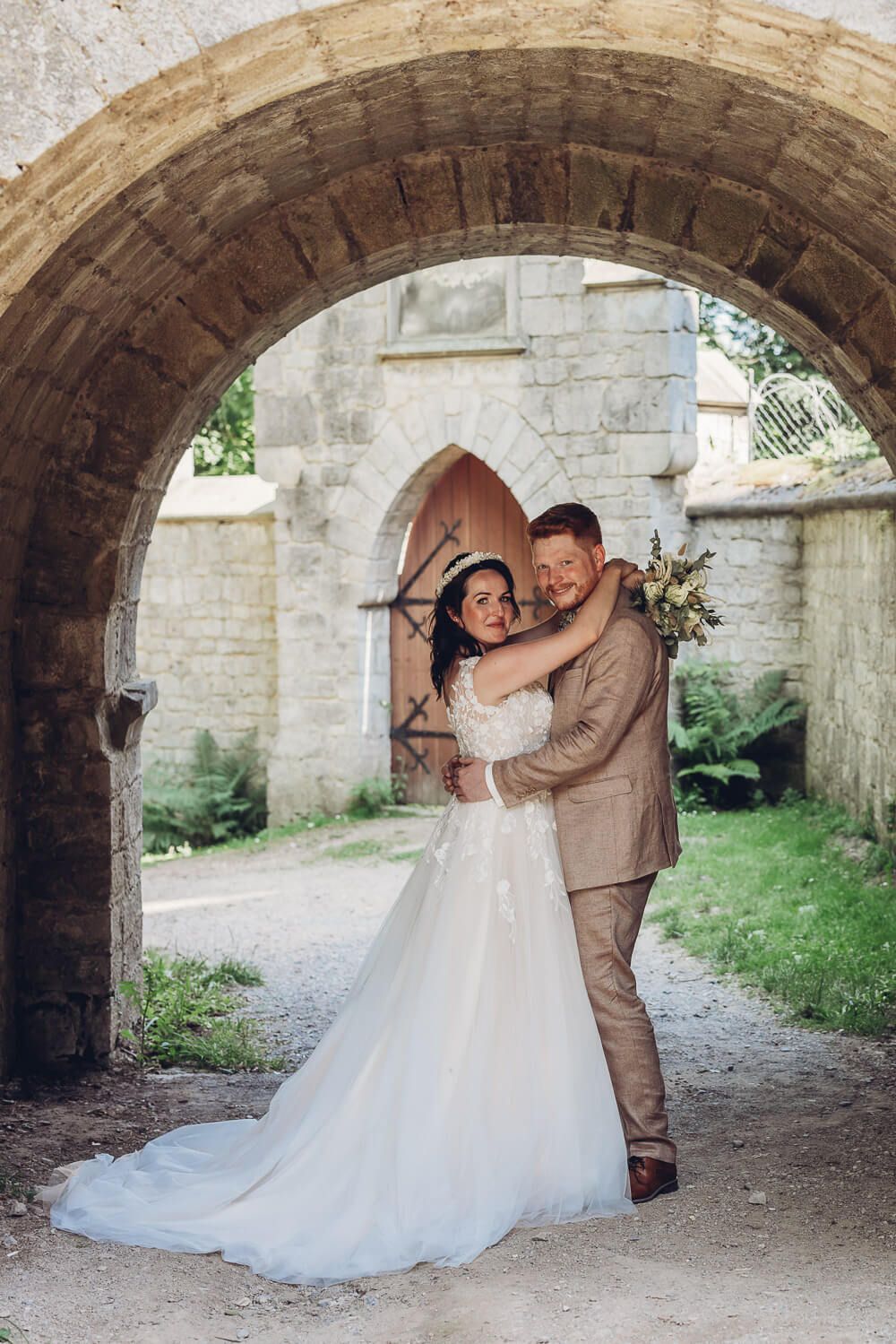 Brautpaar posiert verliebt unter einem historischen Steinbogen bei einem romantischen Hochzeitsshooting in Hildesheim