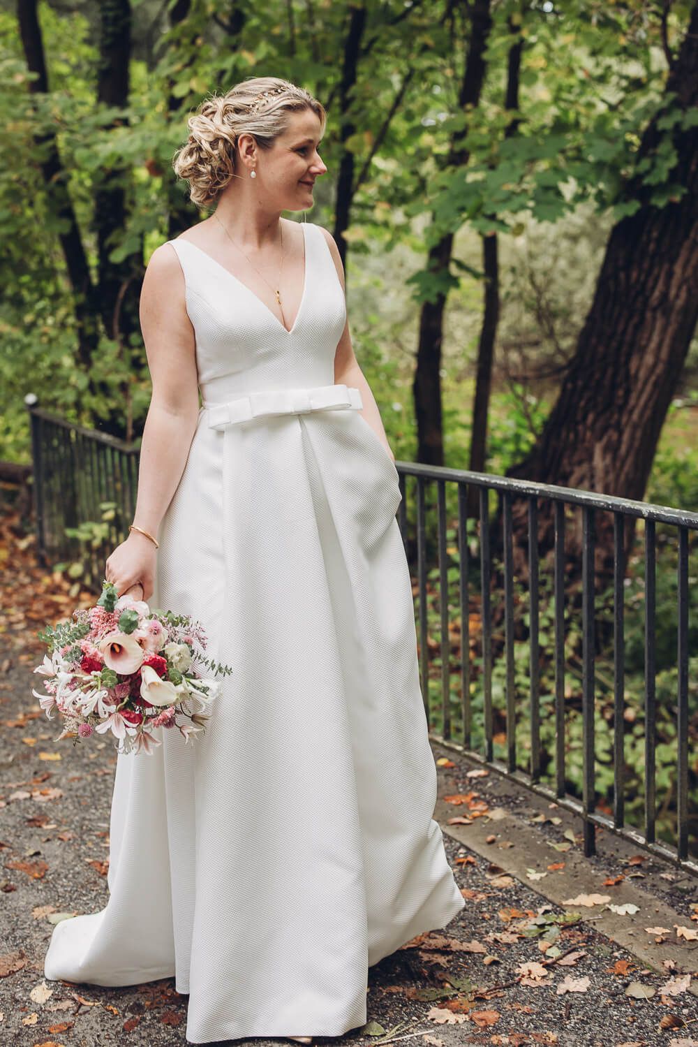 Braut im eleganten weißen Kleid posiert mit Brautstrauß auf einem herbstlichen Weg in Hannover - Fotograf
