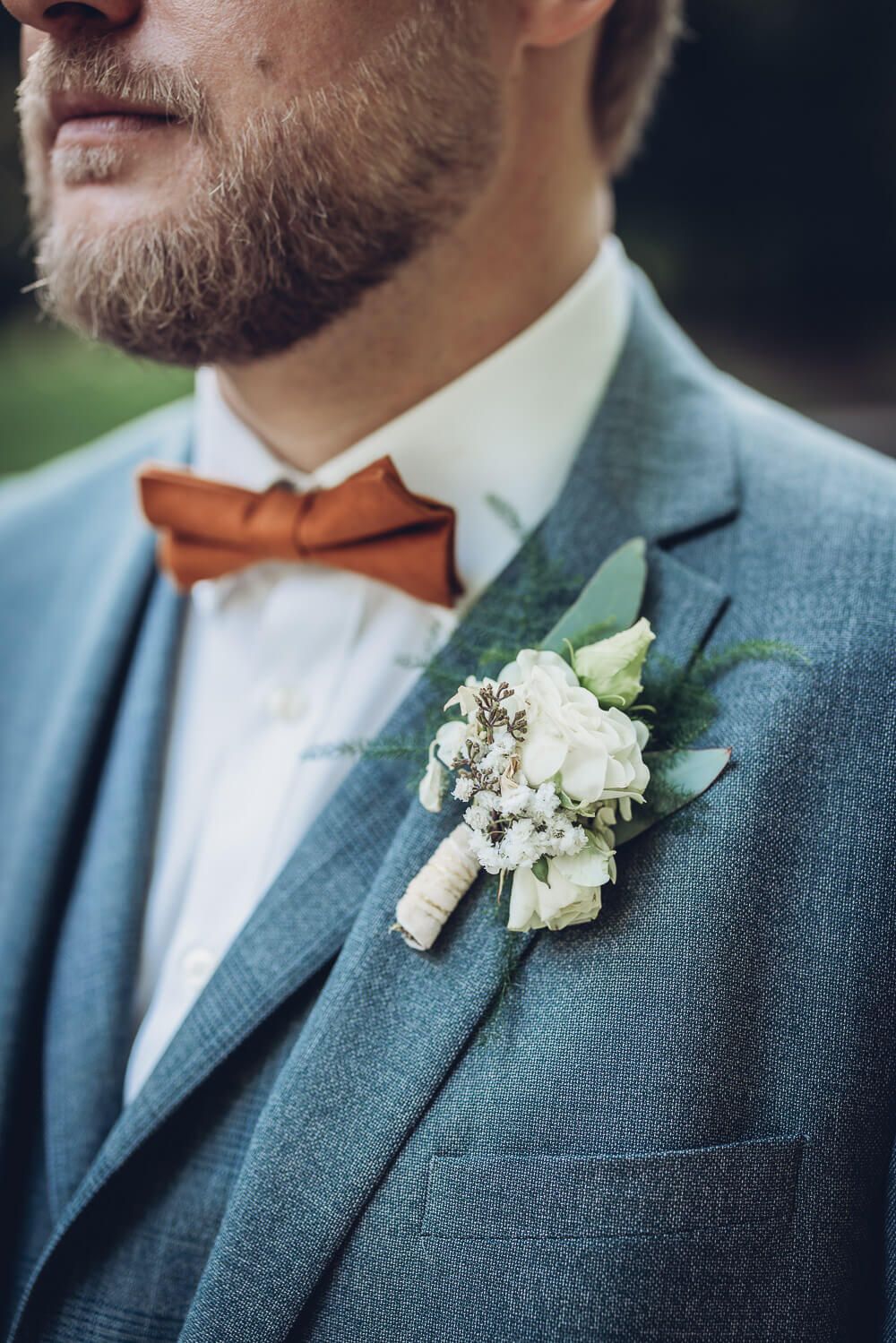 Detailaufnahme des Ansteckers am Hochzeitsanzug des Bräutigams mit Fliege, fotografiert von einem Hochzeitsfotografen in Hannover