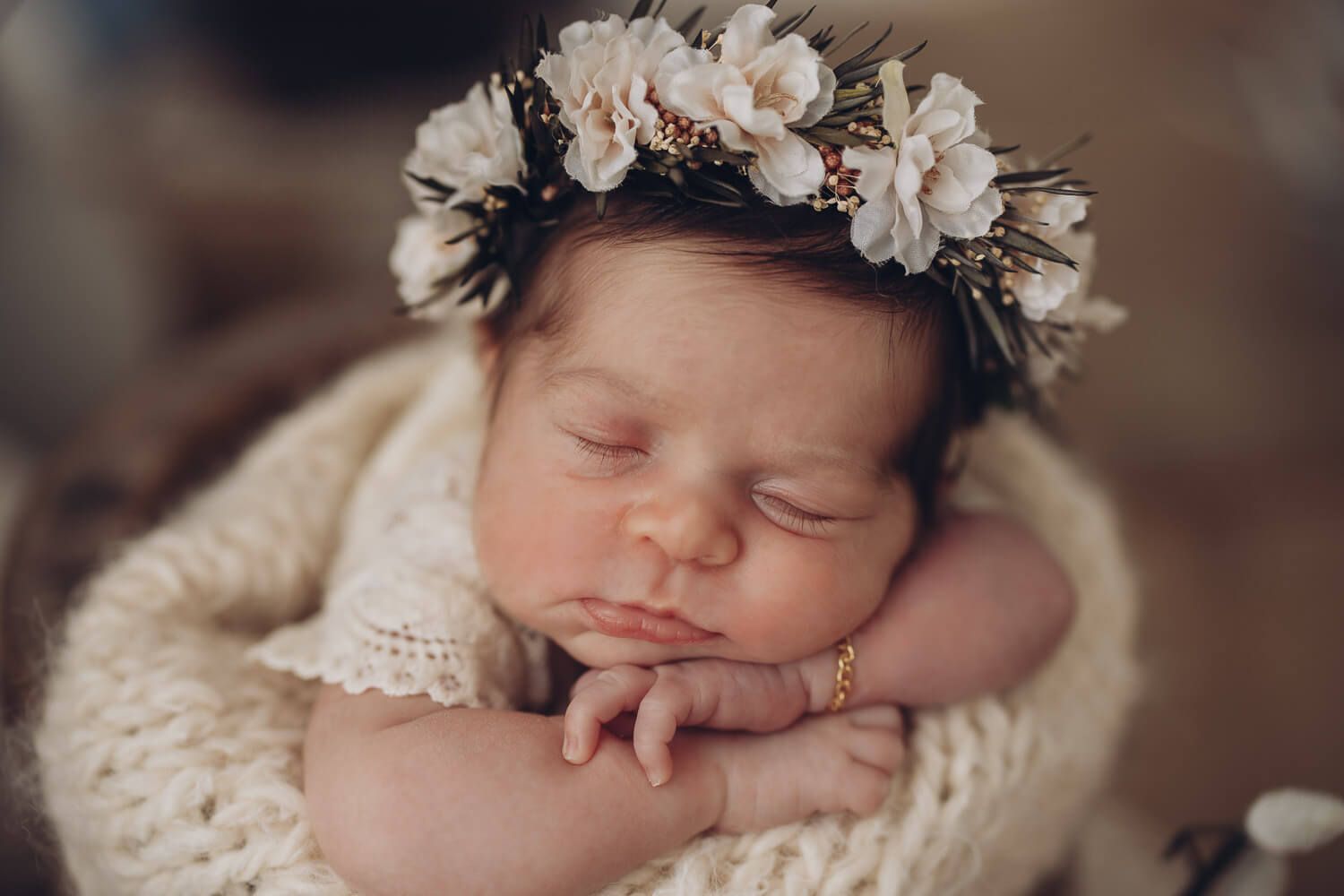 Schlafendes Neugeborenes mit Blumenkranz in einem Körbchen bei einem stilvollen Newborn Shooting in Langenhagen