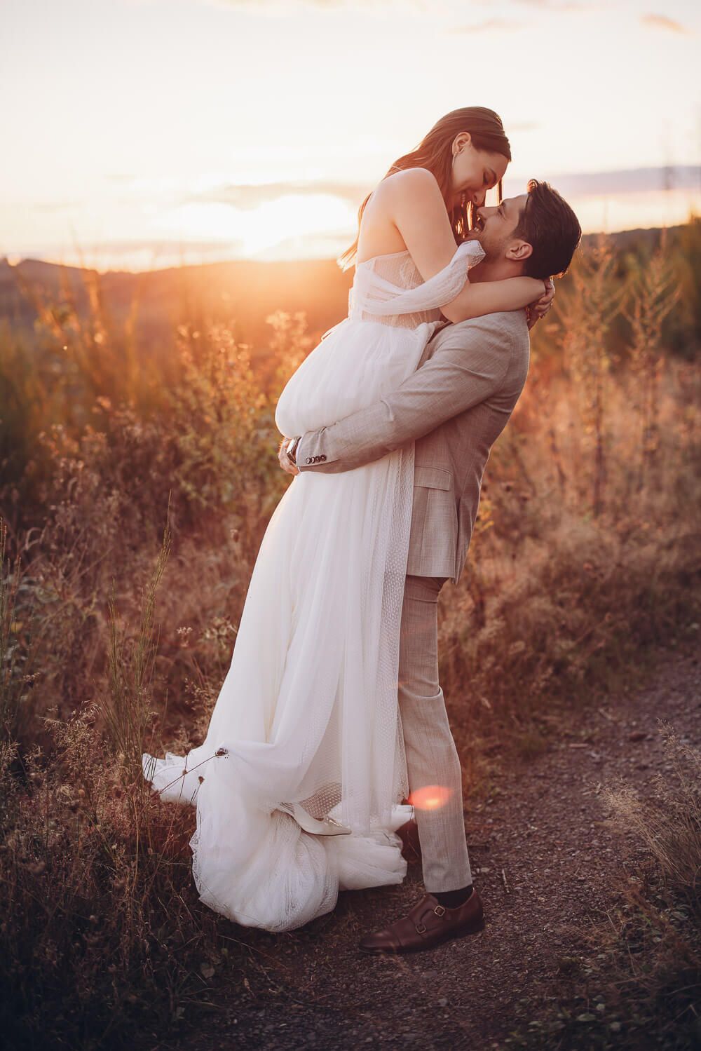 Bräutigam hebt Braut auf Feldweg bei Sonnenuntergang in romantischer Stimmung - Hochzeitsfotoshooting Fotograf in Langenhagen und Garbsen