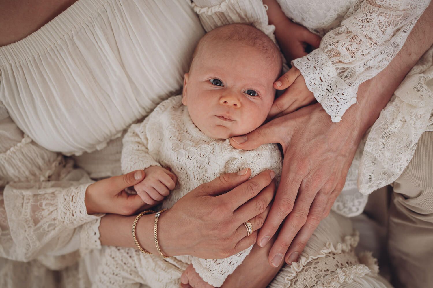 Detailaufnahme im Fotostudio Hannover zeigt ein Baby, umgeben von schützenden Händen der Familie