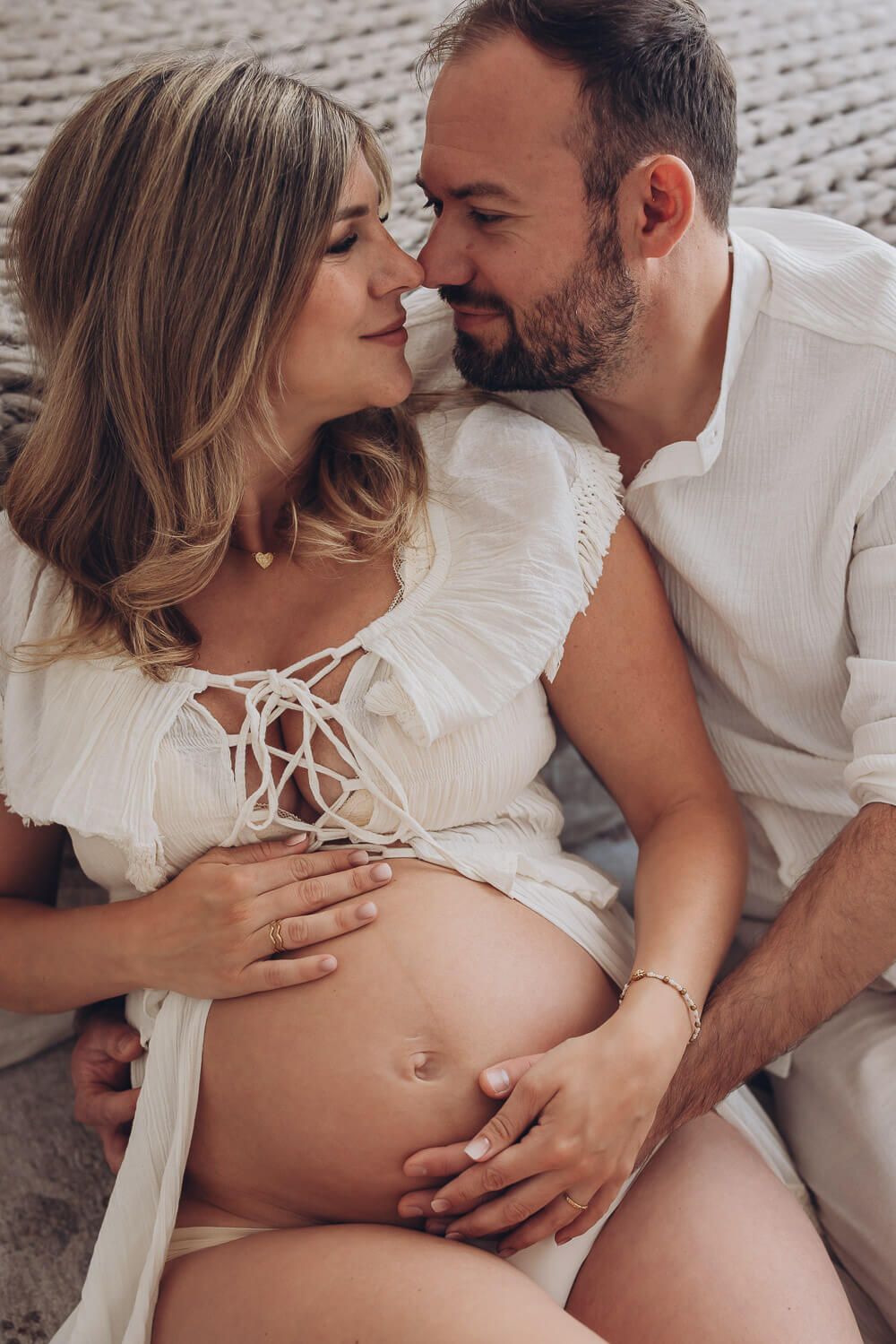 Emotionale Nahaufnahme beim Babybauch Fotoshooting in Wolfsburg – Paar schaut sich liebevoll an und berührt den Babybauch