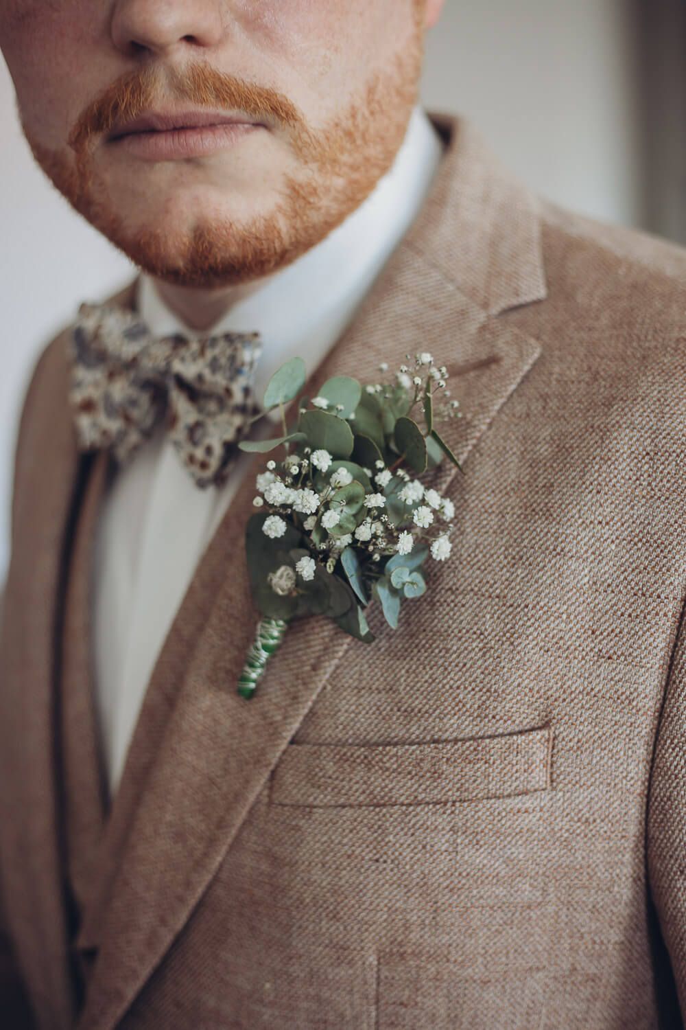 Nahaufnahme der floralen Ansteckblume des Bräutigams mit Eukalyptus und Schleierkraut, festgehalten von einer Hochzeitsfotografin