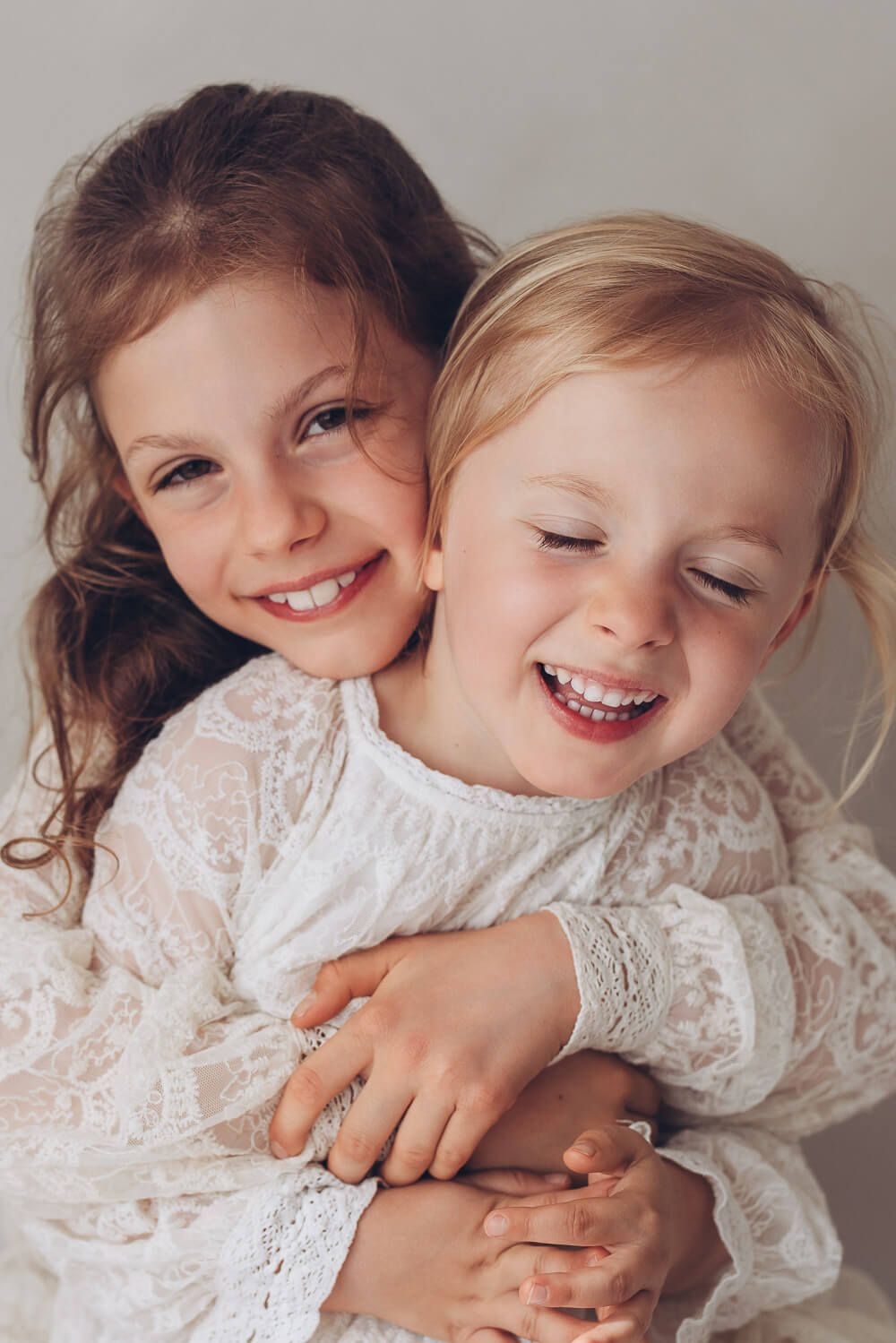 Verspieltes Geschwisterfoto im Fotostudio Hannover, zwei Kinder umarmen sich und lachen fröhlich