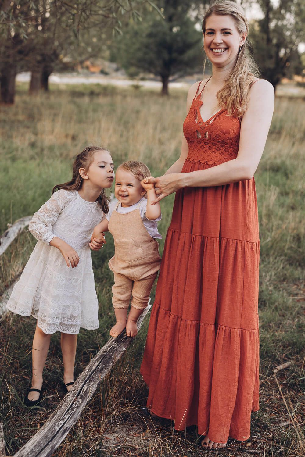 Emotionaler Moment beim Outdoor Shooting Braunschweig, Schwester gibt dem Baby einen Kuss während die Mutter es hält