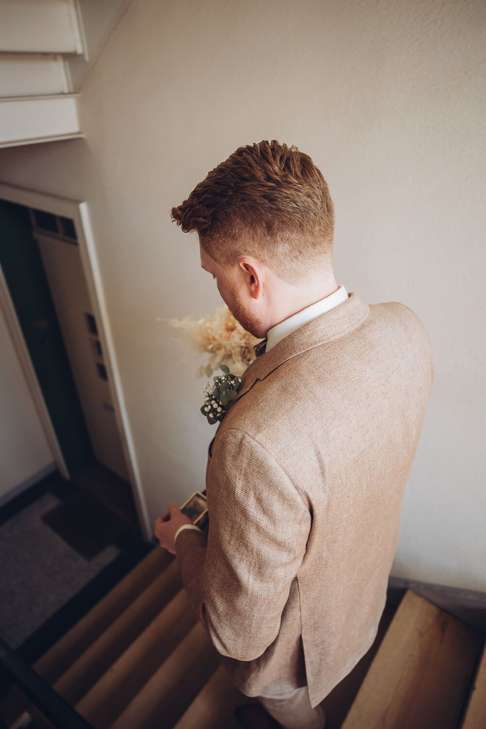 Der Bräutigam steht auf der Treppe und wartet auf die freie Trauung, stimmungsvoll eingefangen von einem Hochzeitsfotografen