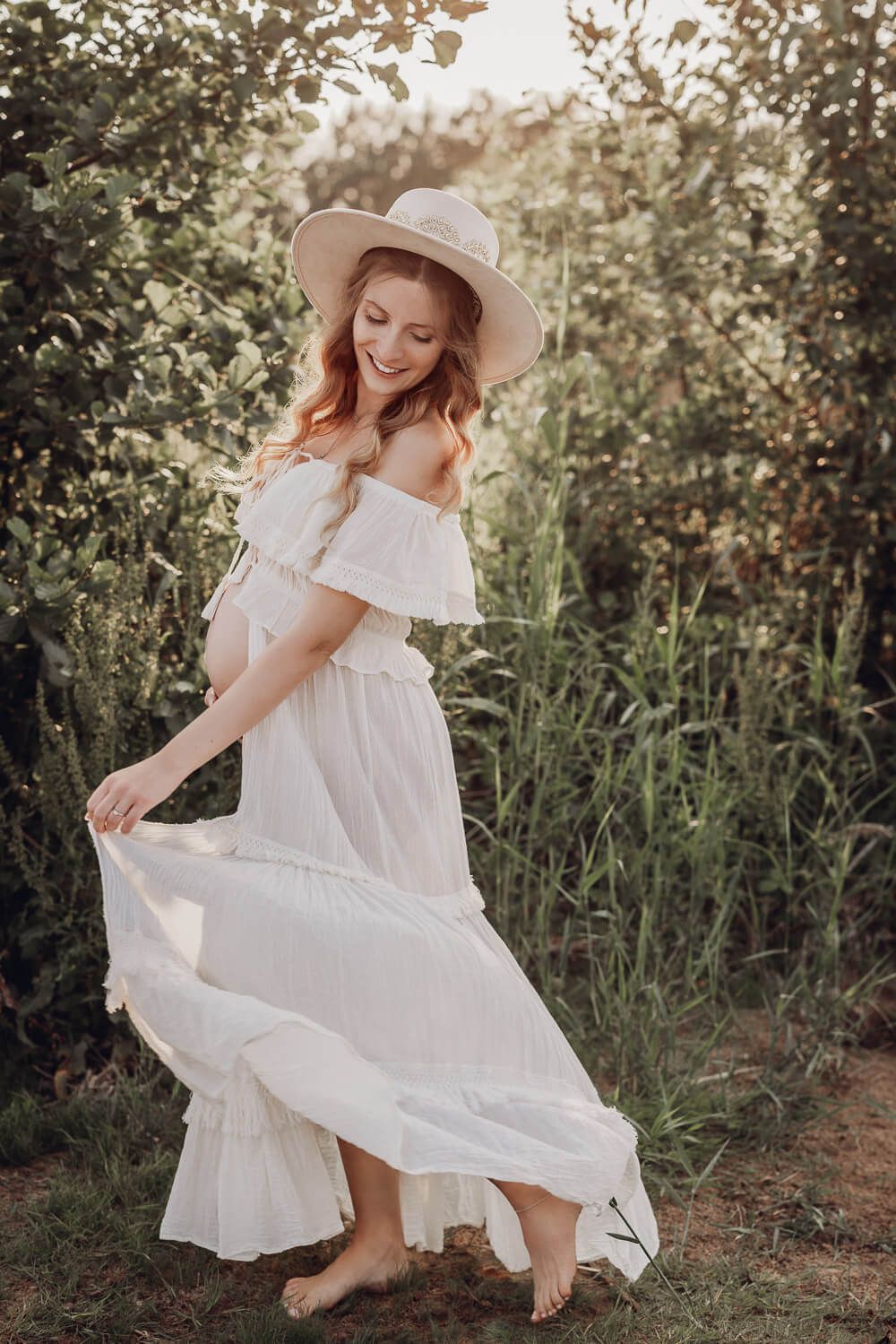 Natürliches Babybauch Fotoshooting in der Natur in Hannover – schwangere Frau dreht sich leicht im boho Kleid