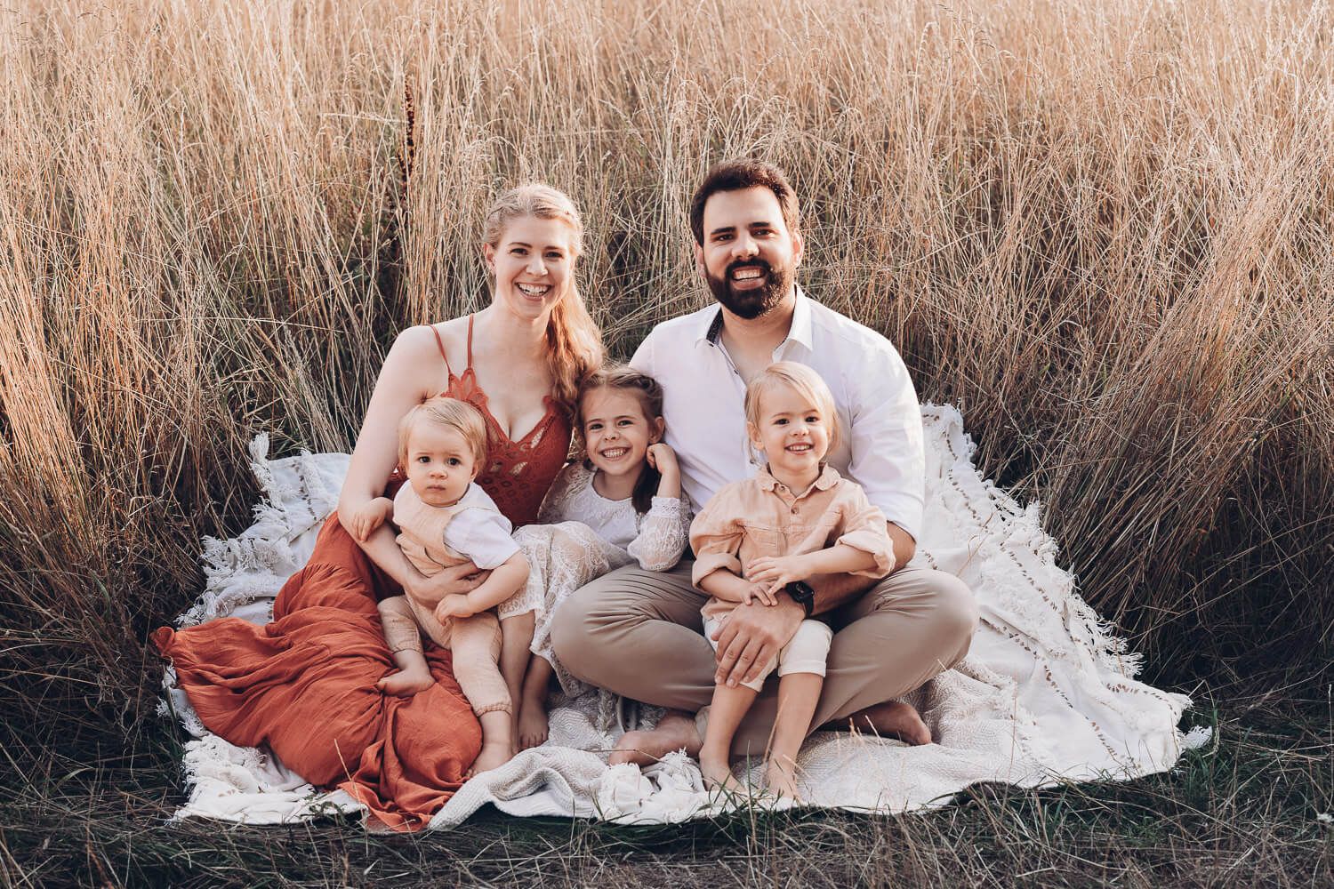 Natürliches Familienfoto beim Outdoorfotoshooting Gehrden, Eltern und Kinder sitzen gemeinsam entspannt auf einer Decke in der Natur