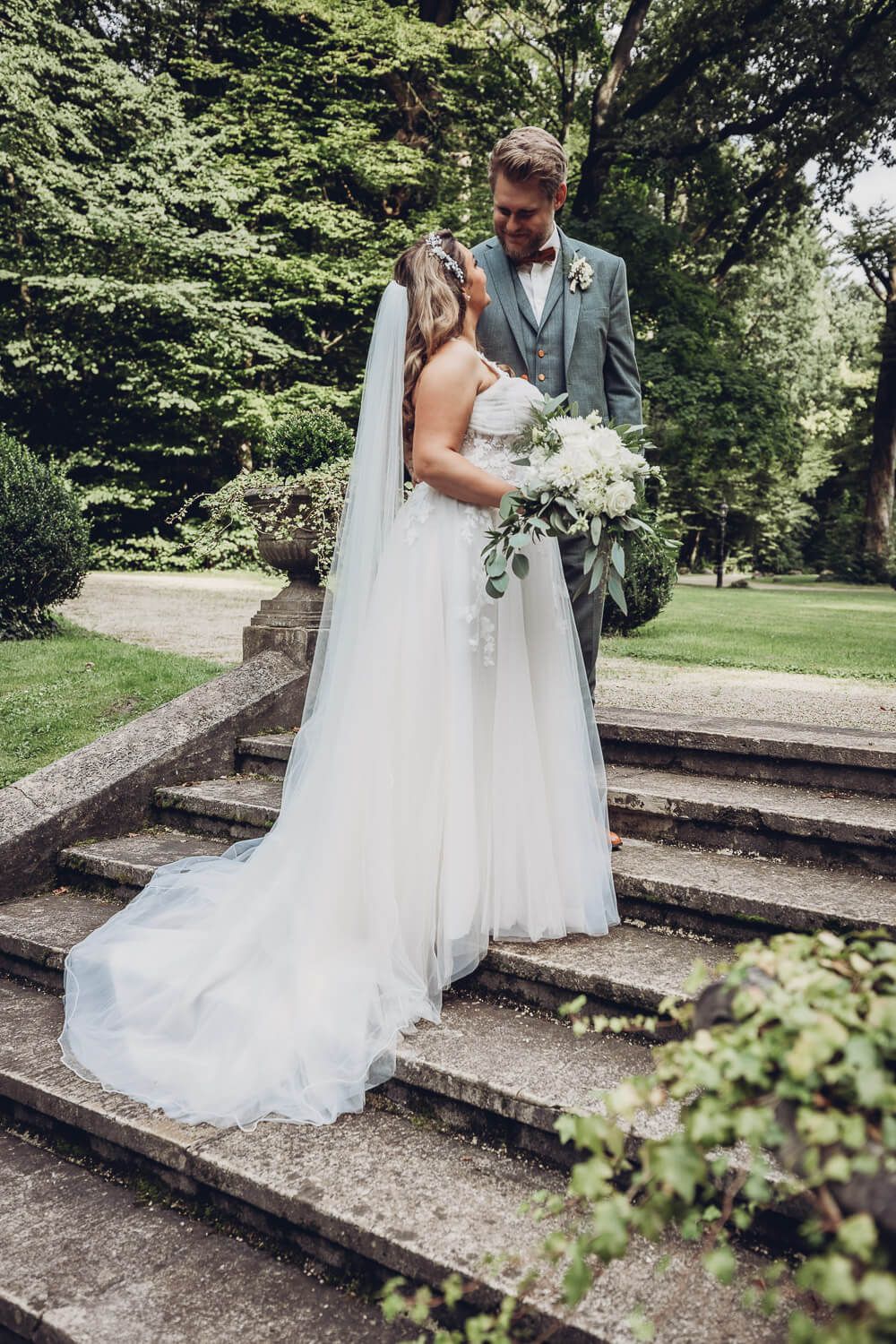 Braut und Bräutigam stehen verliebt auf einer Steintreppe im Park, aufgenommen von einer Hochzeitsfotografin in Garbsen