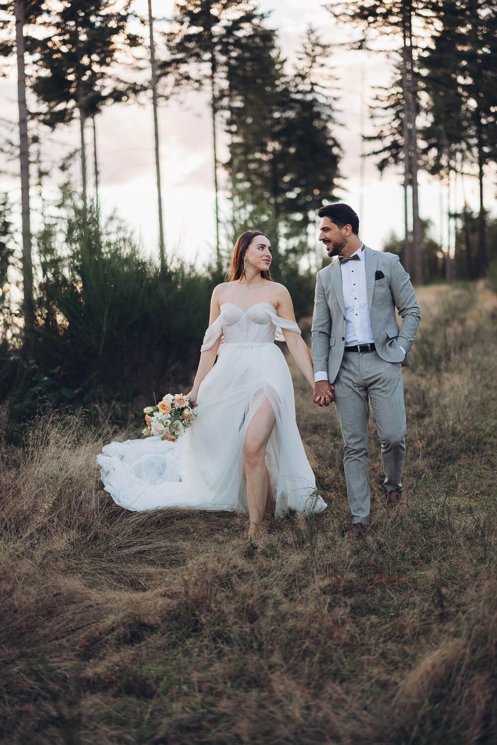 Braut und Bräutigam laufen Hand in Hand durch eine natürliche Kulisse bei einem eleganten Hochzeitsshooting in Hannover