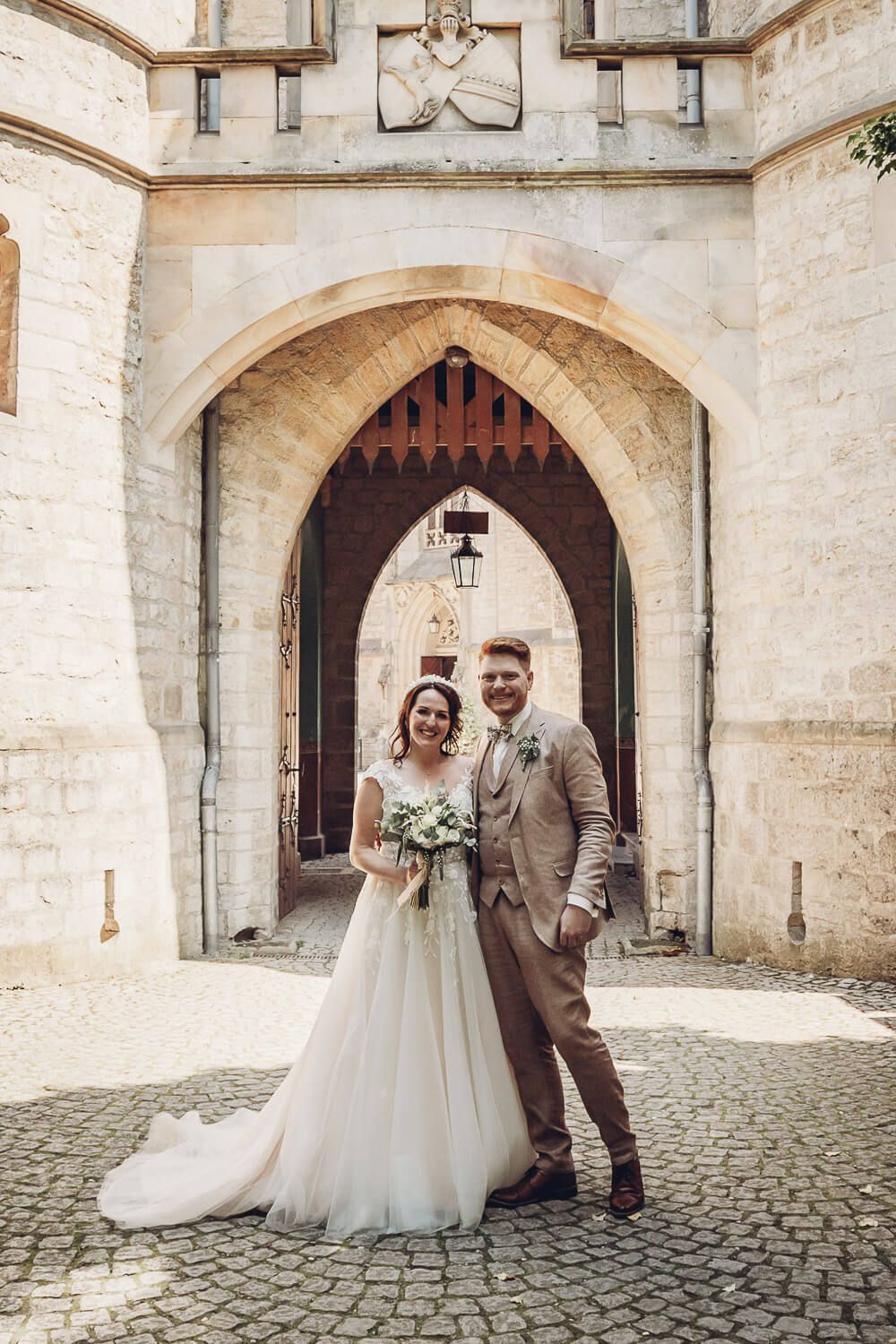 Brautpaar posiert vor einem historischen Tor an der Schloss Marienburg bei Pattensen - Hochzeitsfotografin aus Wolfsburg