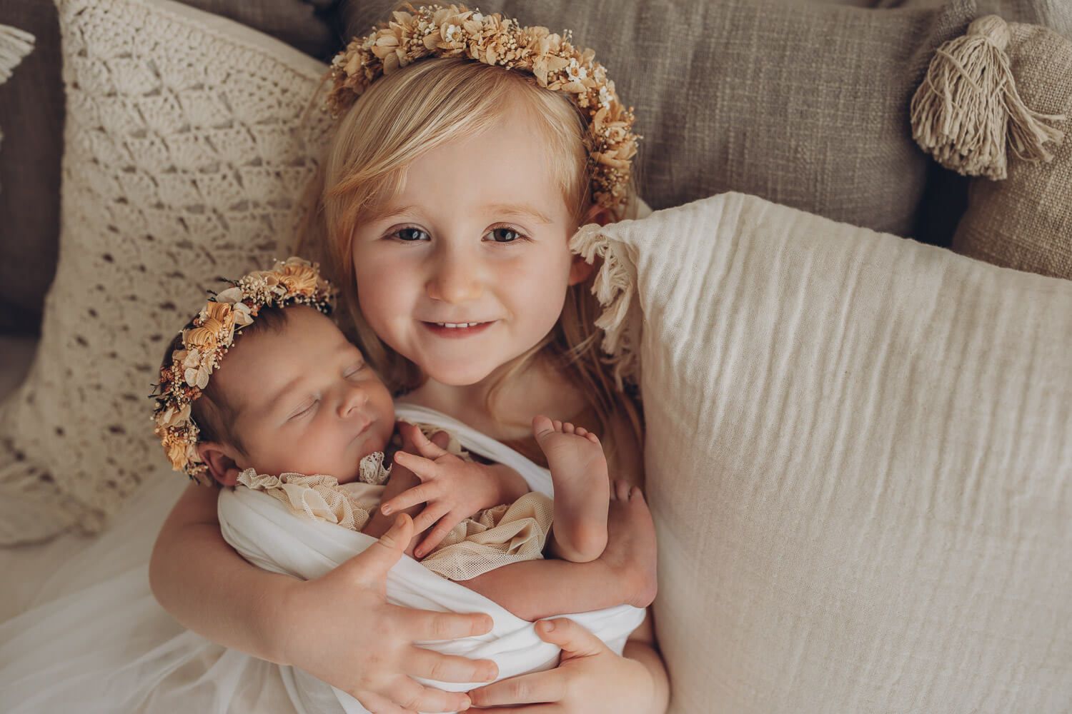 Natürliches Geschwistershooting in Gehrden – großes Schwesterchen hält ihr Neugeborenes beim Baby Fotoshooting im Boho Stil