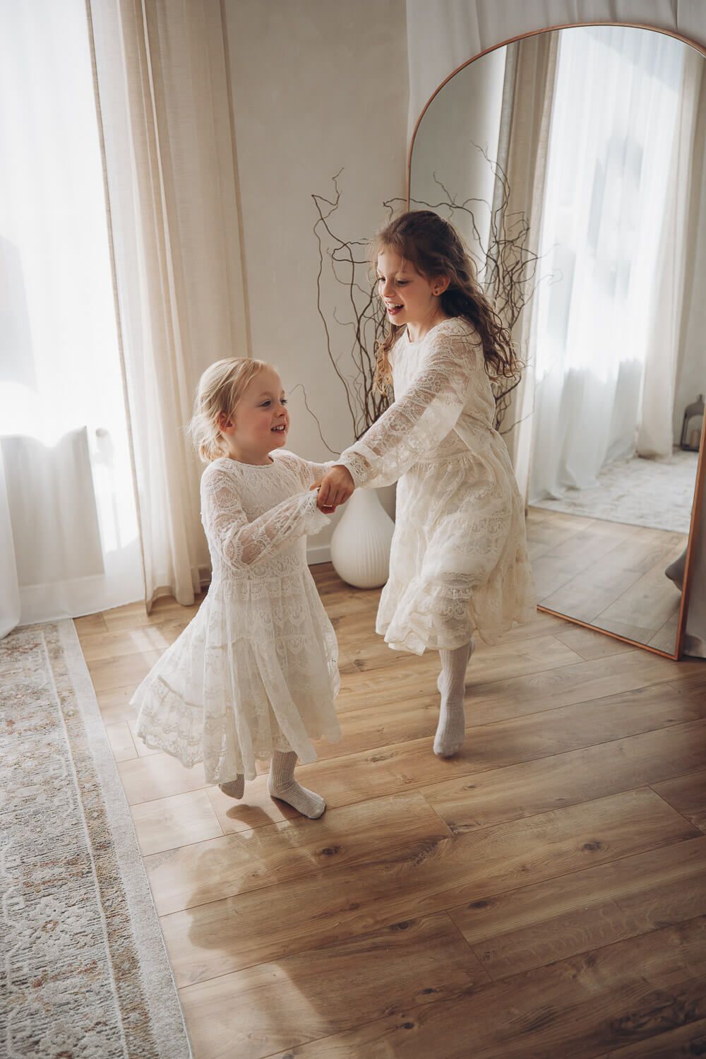 Zwei Mädchen tanzen lachend im natürlichen Licht eines Studios – lebendige Kinderfotografie in Hannover und Celle