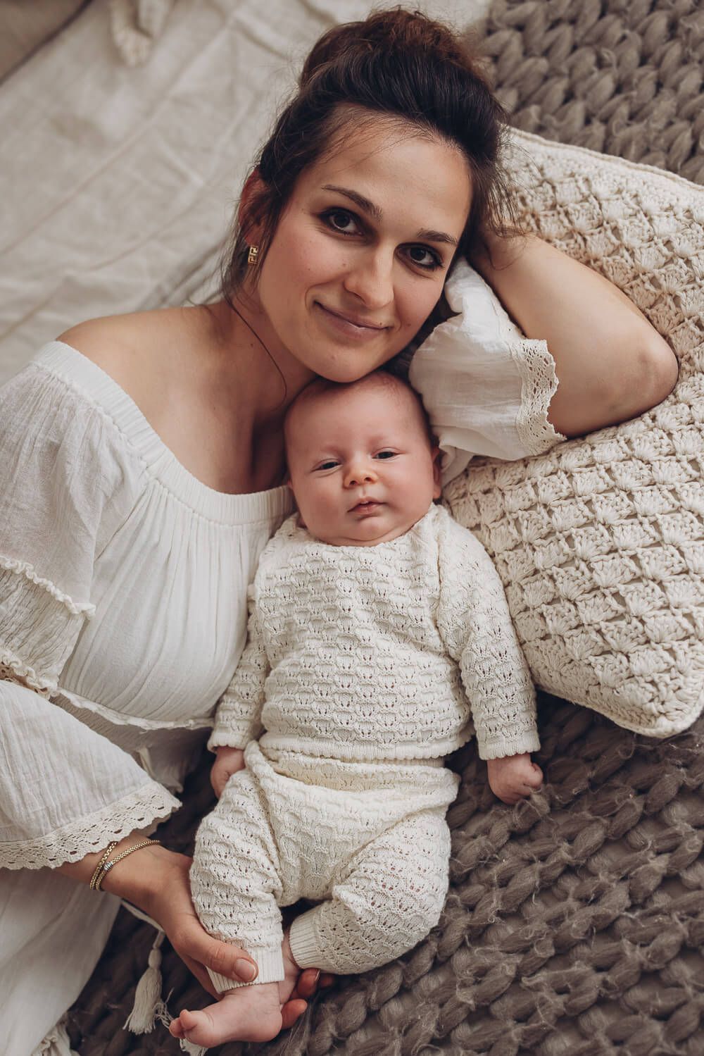 Mutter liegt entspannt neben ihrem Baby auf einer weichen Decke – natürliche Neugeborenenfotografie in Hannover und Pattensen