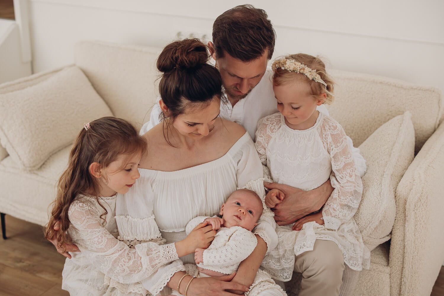 Harmonisches Familienfoto im Fotostudio Hannover mit Eltern und drei Kindern, alle schauen liebevoll auf das Baby