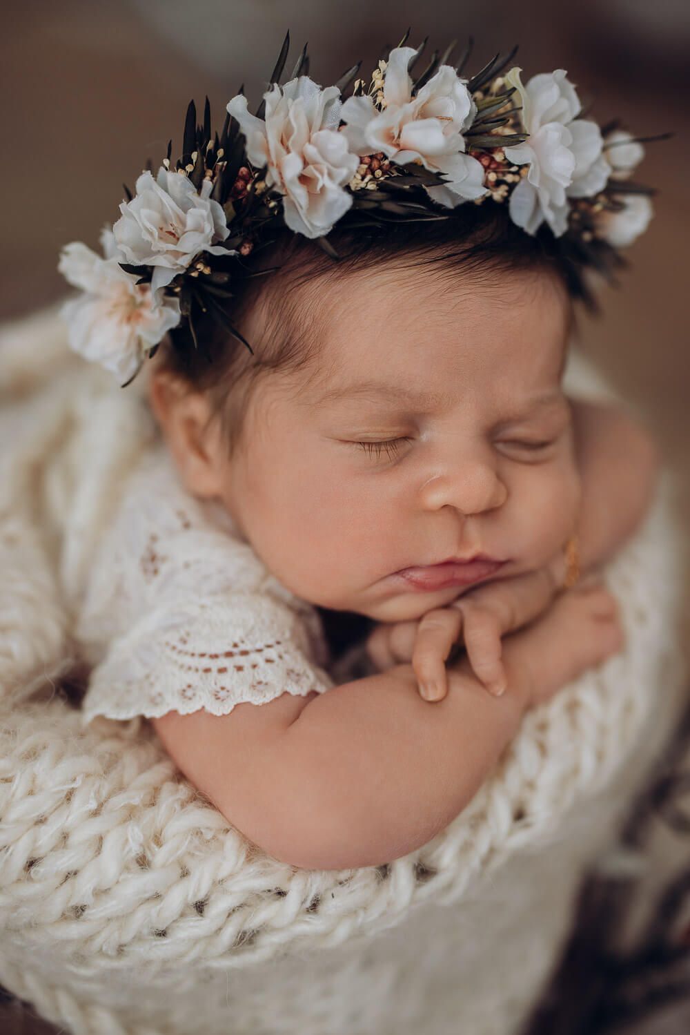 Nahaufnahme eines schlafenden Neugeborenen mit Blumenkranz bei einem liebevollen Babyshooting in Braunschweig