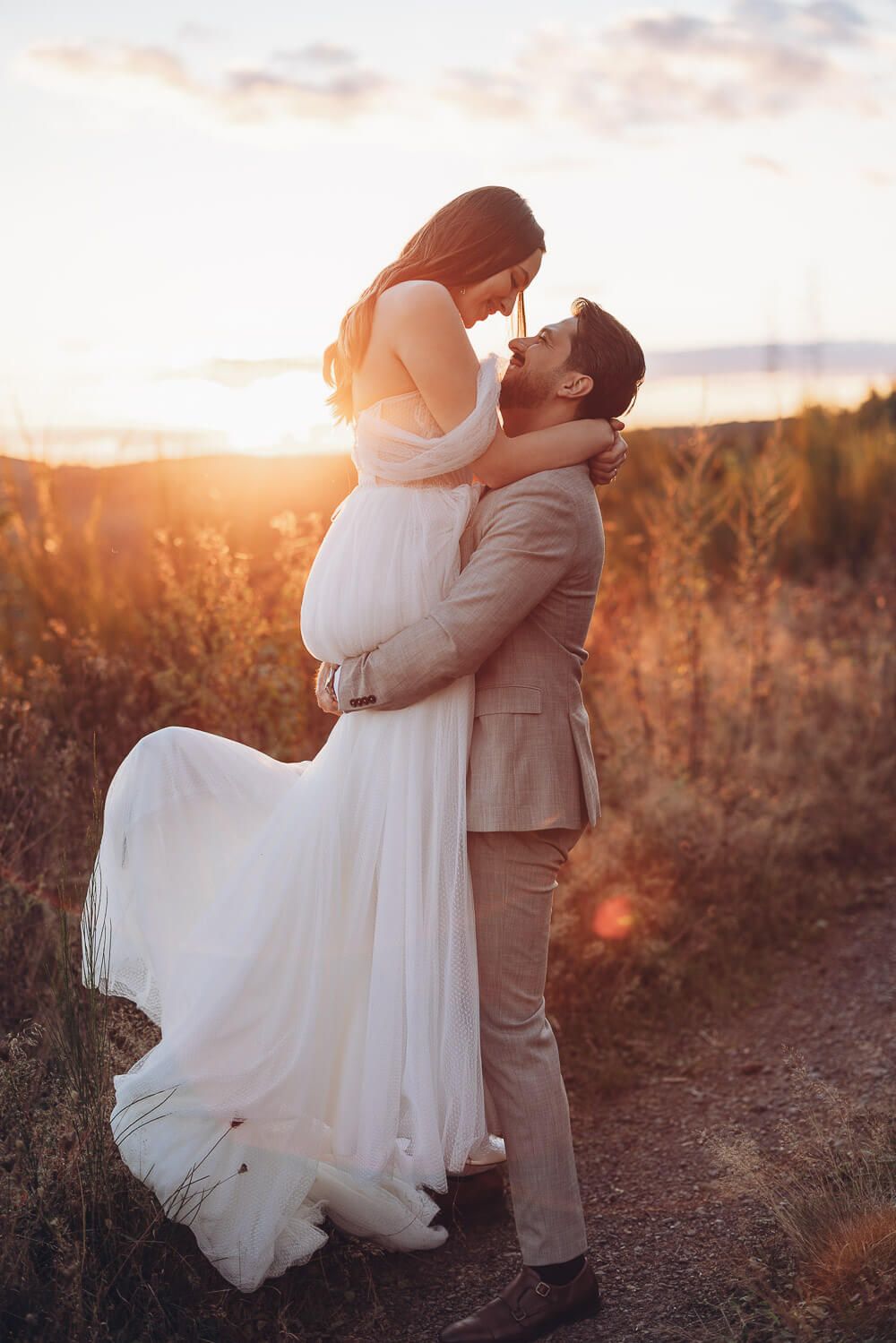 Bräutigam hebt die Braut liebevoll hoch, während beide im Sonnenuntergang lachen, bei einem emotionalen Hochzeitsshooting in Hannover