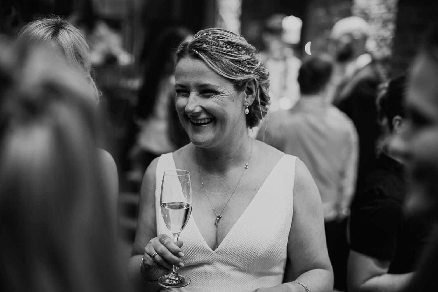 Fröhliche Braut mit Sektglas während des Empfangs, lebendig und natürlich fotografiert bei einer Hochzeit in Hannover