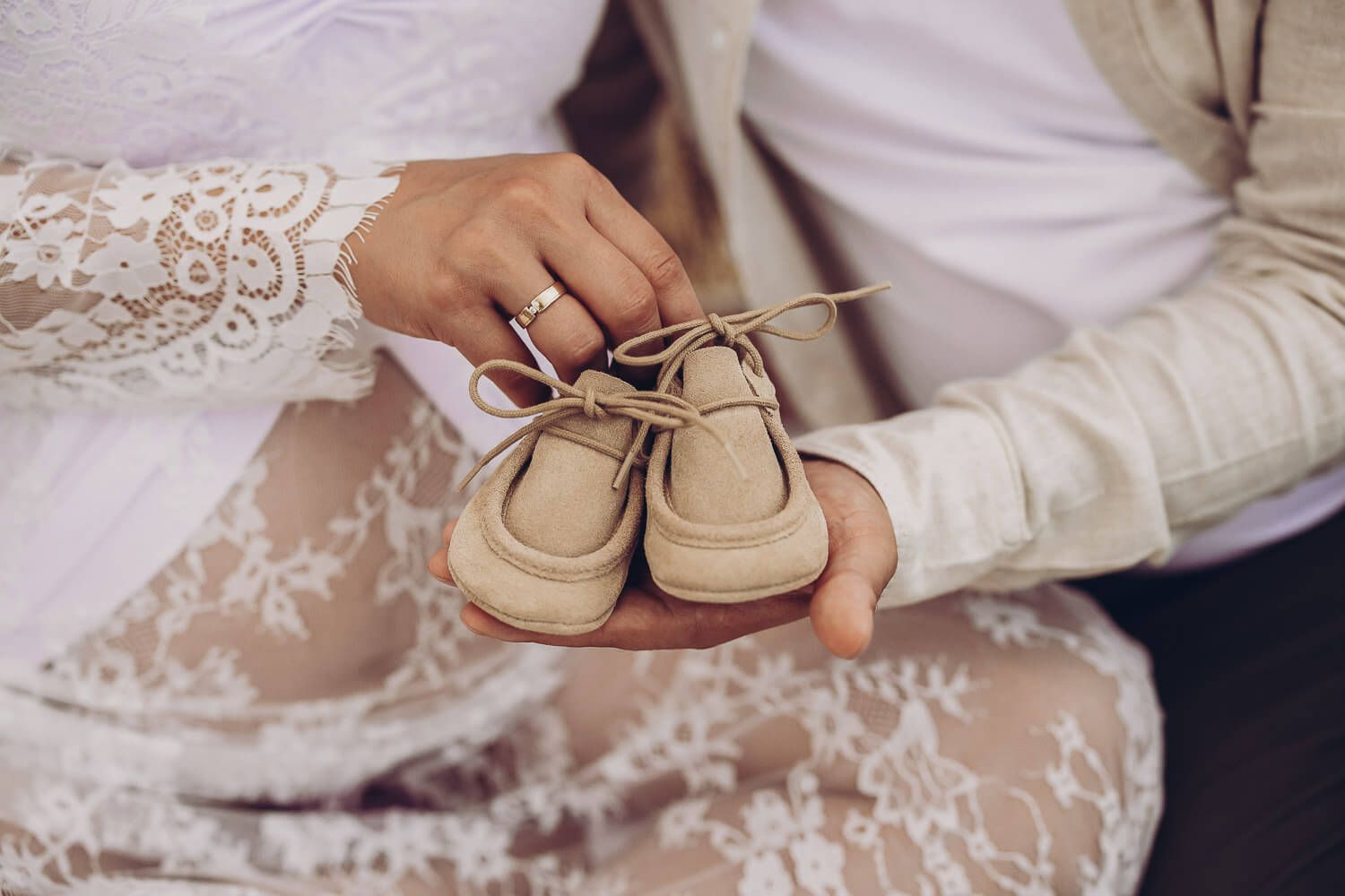 Detailaufnahme von Händen mit Babyschuhen als Symbol für Schwangerschaft - Babybauchshooting in Hannover