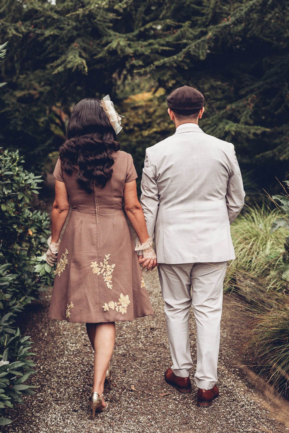 Brautpaar spaziert Hand in Hand durch einen Gartenweg, festgehalten von einer Hochzeitsfotografin in Hannover
