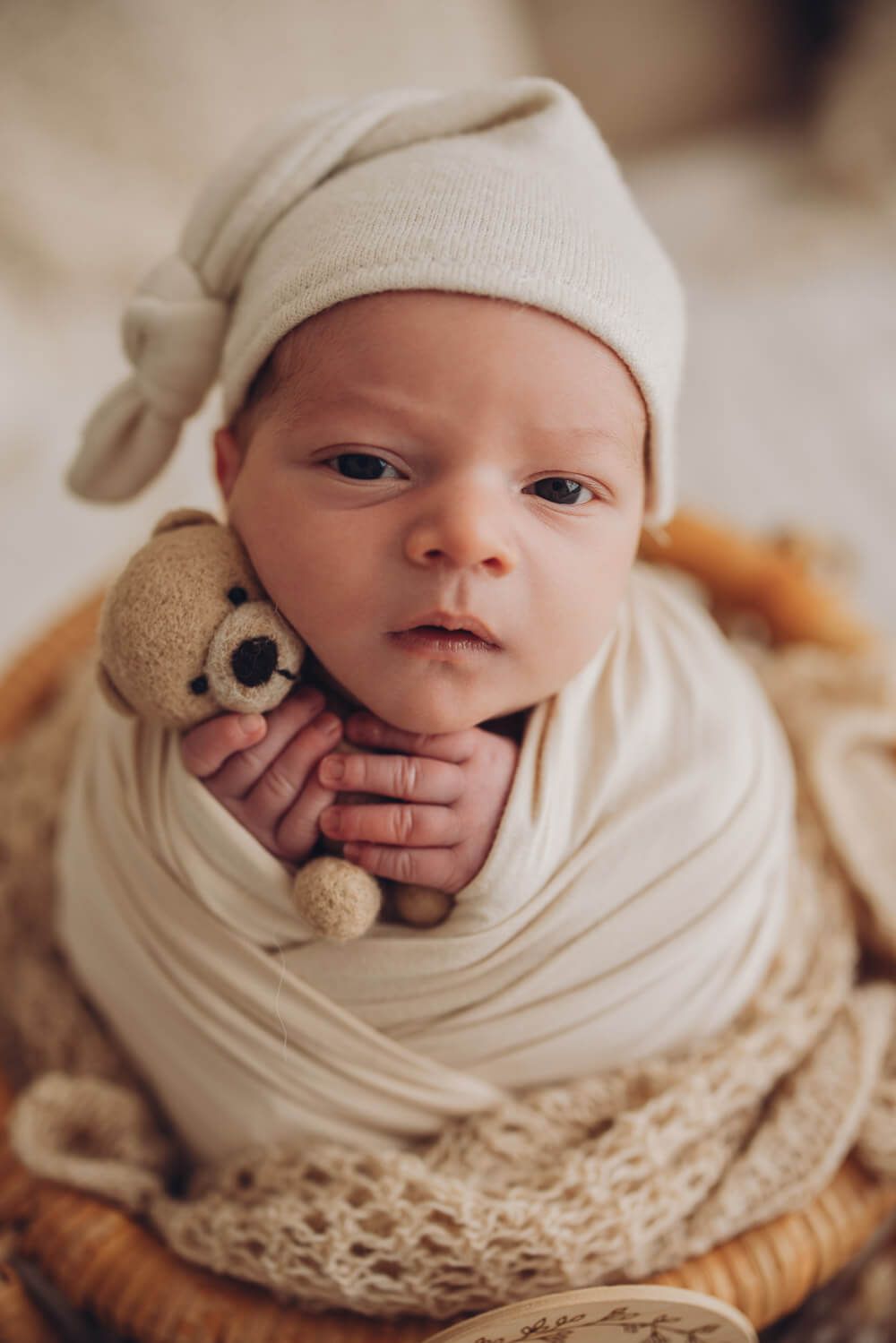 Neugeborenes mit offenen Augen und Mützchen bei einem liebevollen Baby Fotoshooting in Hannover