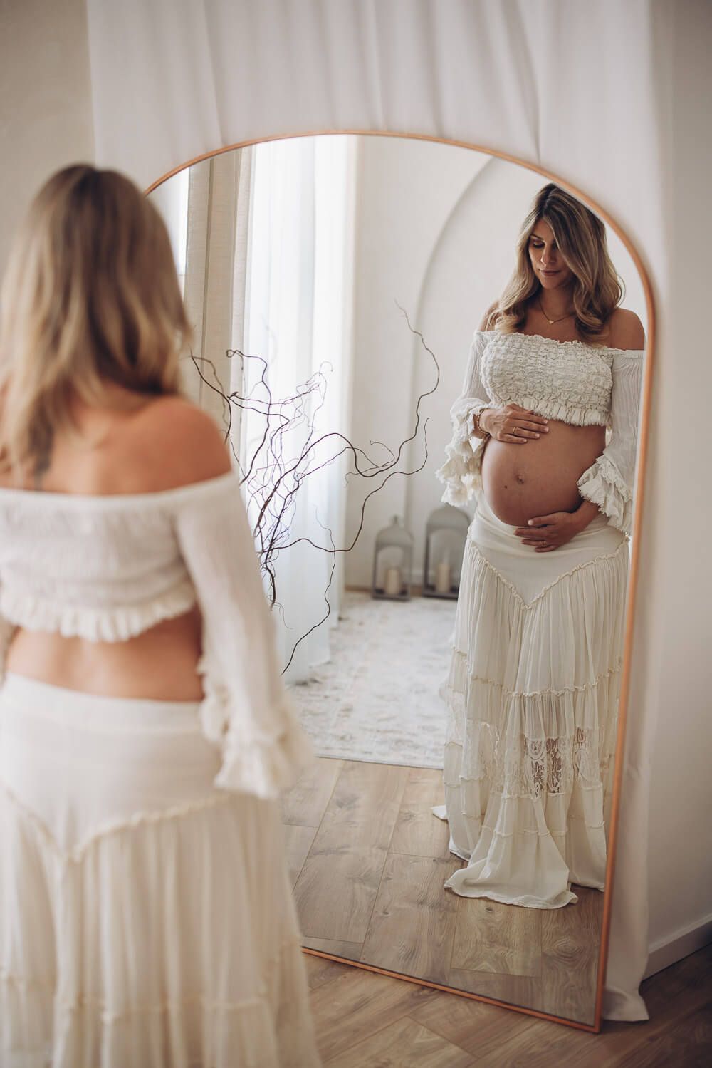 Künstlerisches Babybauch Fotoshooting in Bad Nenndorf – werdende Mutter betrachtet sich im Spiegel und hält ihren Bauch