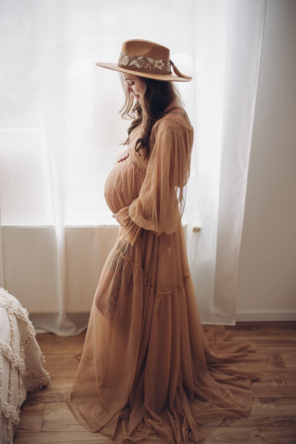 Schwangere Frau im Boho Kleid mit Hut bei einem stilvollen Babybauch Fotoshooting in Wunstorf