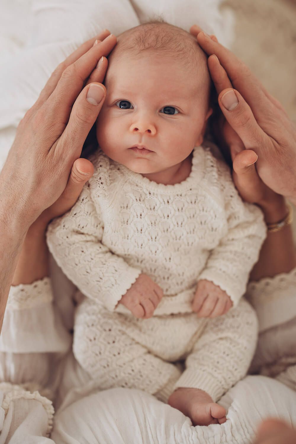 Neugeborenes wird sanft von den Händen der Eltern gehalten – liebevolle Babyfotografie in Hannover, Garbsen und Langenhagen
