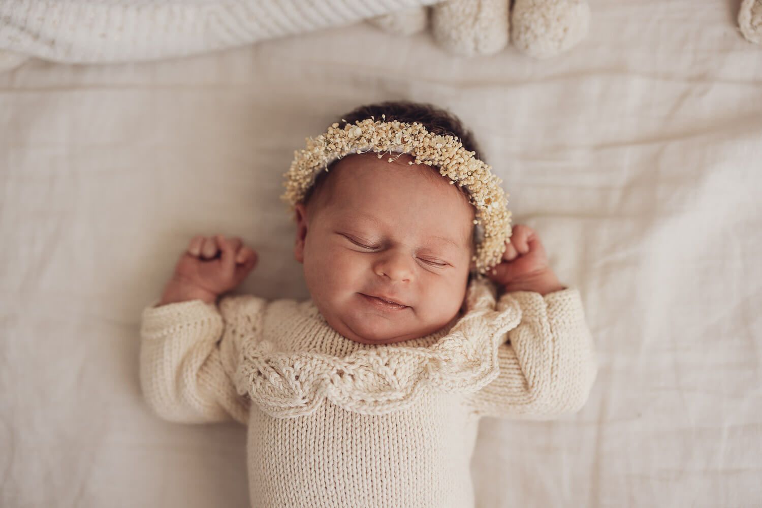 Liebevolles Neugeborenen Fotoshooting in Hildesheim – schlafendes Baby mit floralem Stirnband und Strickkleidung