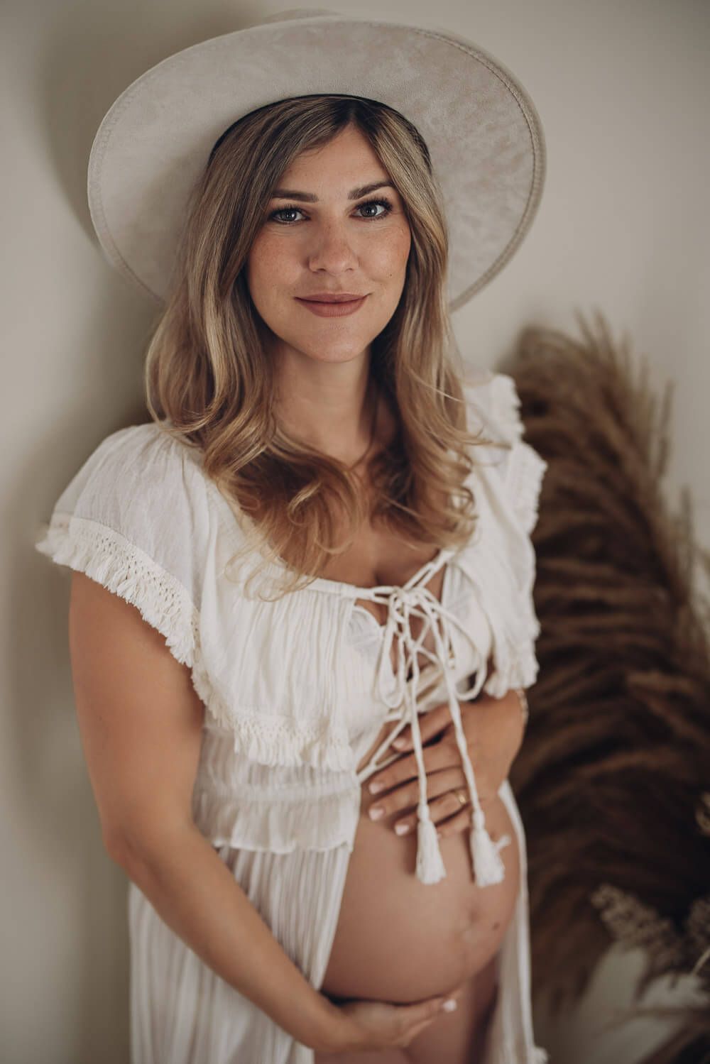 Natürliches Babybauch Fotoshooting in Peine – schwangere Frau mit Hut und Boho Kleid schaut entspannt in die Kamera
